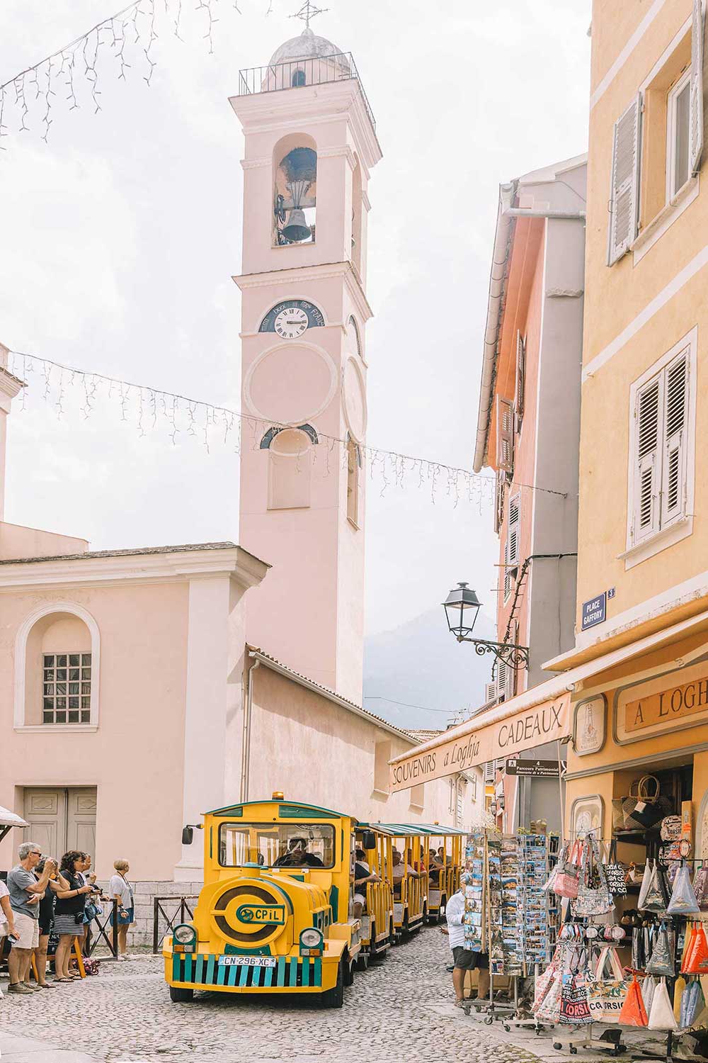yellow-train-running-through-corte-main-square-with-pink-cathedral-in-corsica-france